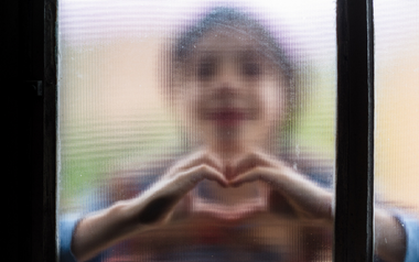 Boy making heart sign through glass
