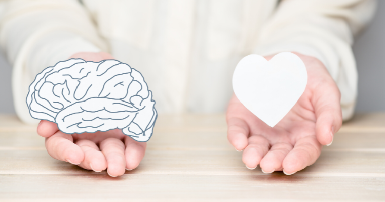 Hands holding paper cut outs in the shape of a brain and a heart
